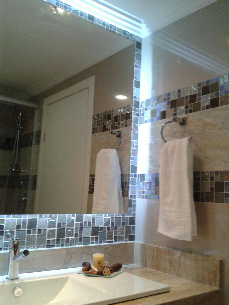 Banheiro com espelho e parede e faixas laterais com pastilhas coloridas