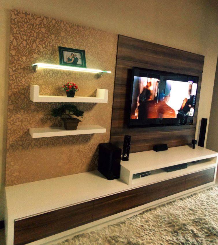 Sala pequena decorada com painel de tv, rack, prateleiras tapete.