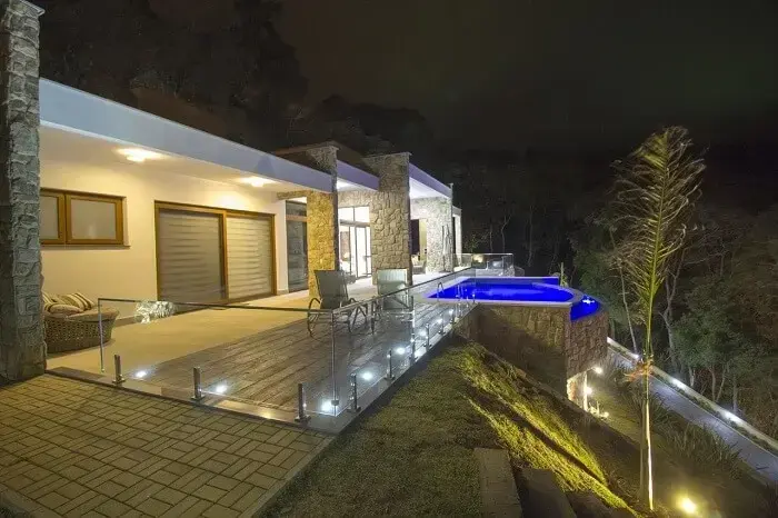 Casas com piscina com borda infinita iluminada no período noturno