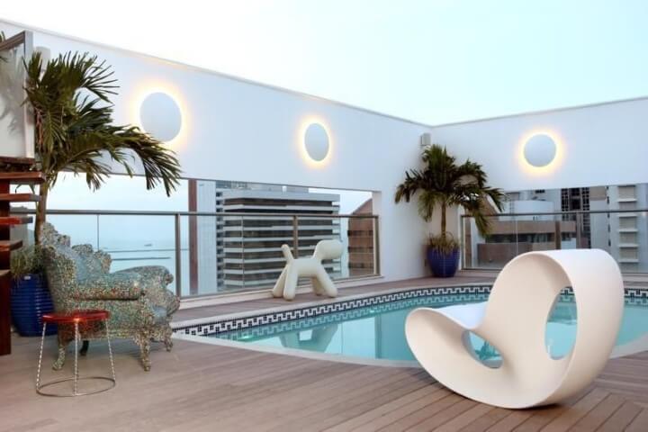 Piscinas pequenas com piso de deck em volta e poltrona branca Projeto de Rodrigo Maia