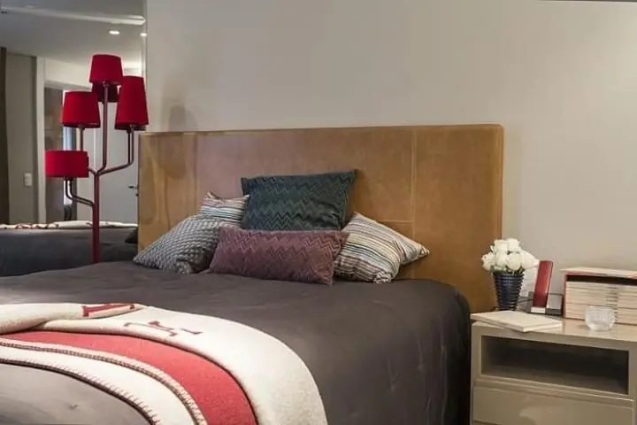Abajur para chão vermelho ao lado da cama de casal Projeto de Mauricio Karam