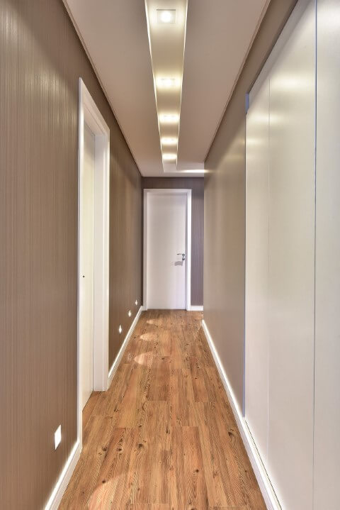 Corredor com pisos que imitam madeira Projeto de Tetriz Arquitetura