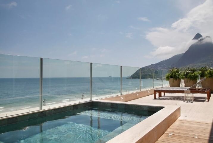 Deck com piscina pequena suspensa e vista para a praia Projeto de Izabela Lessa