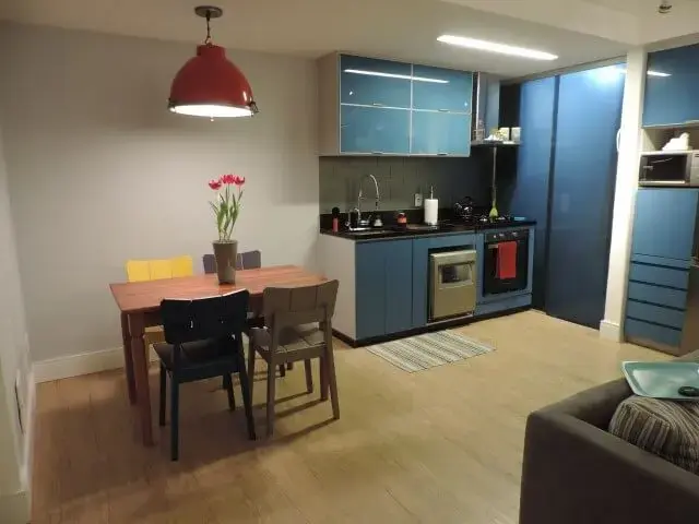 Cozinha colorida com armários azuis e cadeiras coloridas Projeto de Anderluce Rodrigues