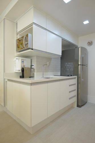 Cozinha compacta com armários planejados brancos e parte do revestimento de azulejo metro white Projeto de Ravaglia Philot