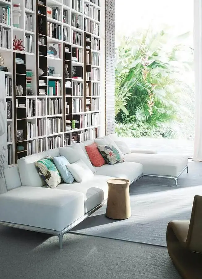 sofá com chaise branco em sala com prateleiras de livros