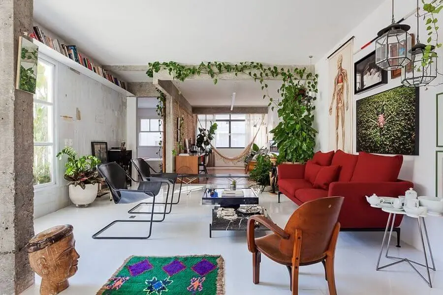 sofá vermelho para decoração de sala com muitas plantas e poltrona de madeira Foto Pinterest