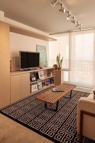 Sala de TV com mesa de centro de madeira e tapete geométrico Projeto de Go Up Arquitetura