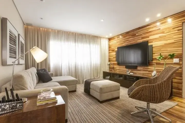 Sala de TV com parede revestida de madeira e móveis discretos