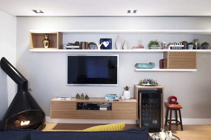 Sala de TV com prateleiras brancas e de madeira Projeto de D2N Arquitetura