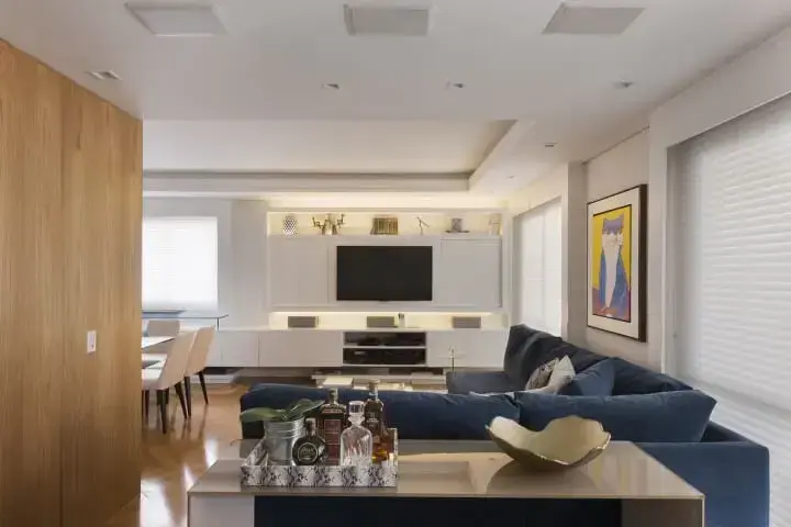 Sala de TV integrada com sala de janta e sofá em L azul Projeto de Gustavo Motta
