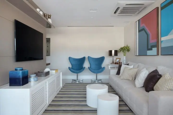 Sala de TV com móveis grandes brancos e toque coloridos Projeto de Mariana Martini