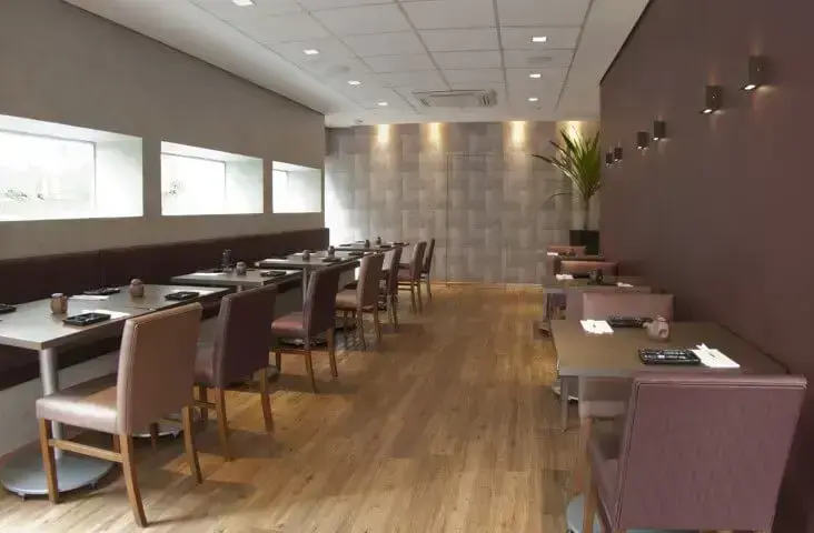 Salão de restaurante com piso vinílico e decoração marrom e roxa Projeto de Monica Spada Durante