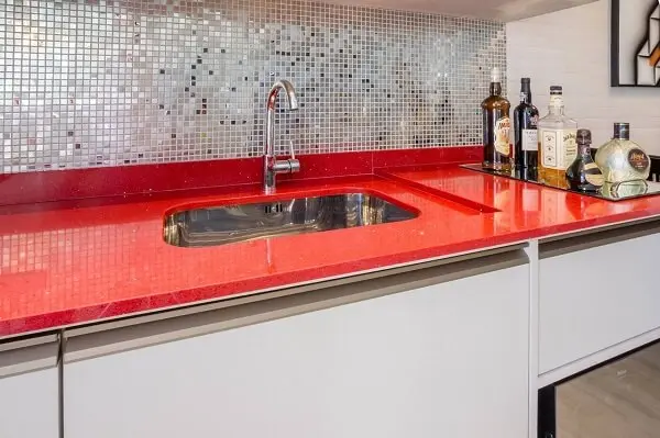 A pia da cozinha vermelha se destaca na decoração do ambiente
