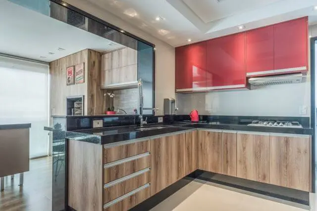 Cozinha integrada com armário de cozinha de madeira e vermelho Projeto de Cássia Giacomazzi