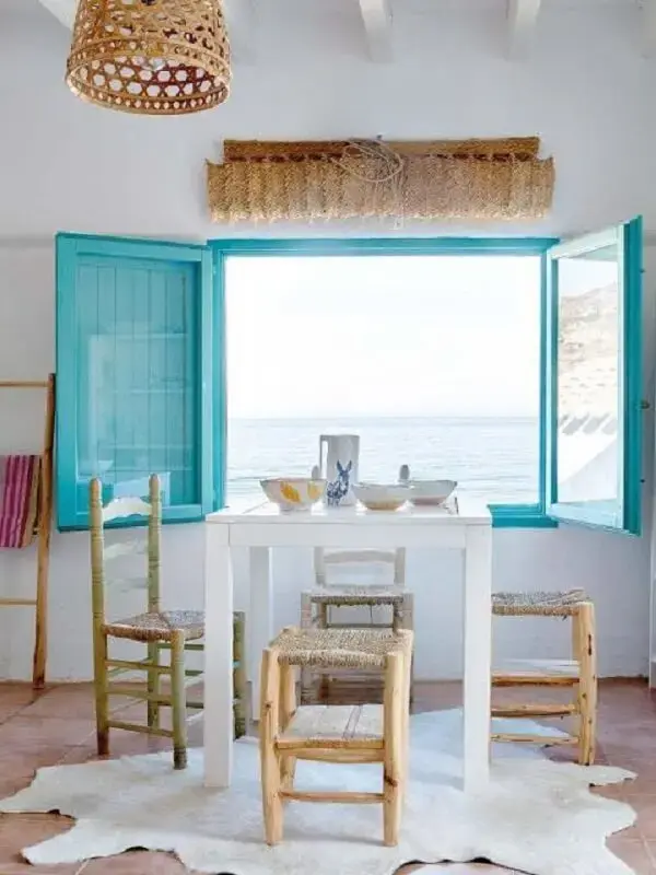 A janela azul da casa de praia nos convida a olhar à vista