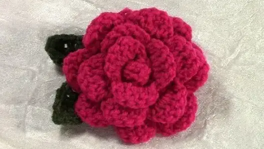 Flor de crochê rosa com folha verde escura