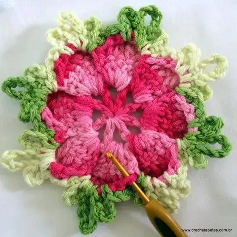Flor de crochê rosa com folhas verdes