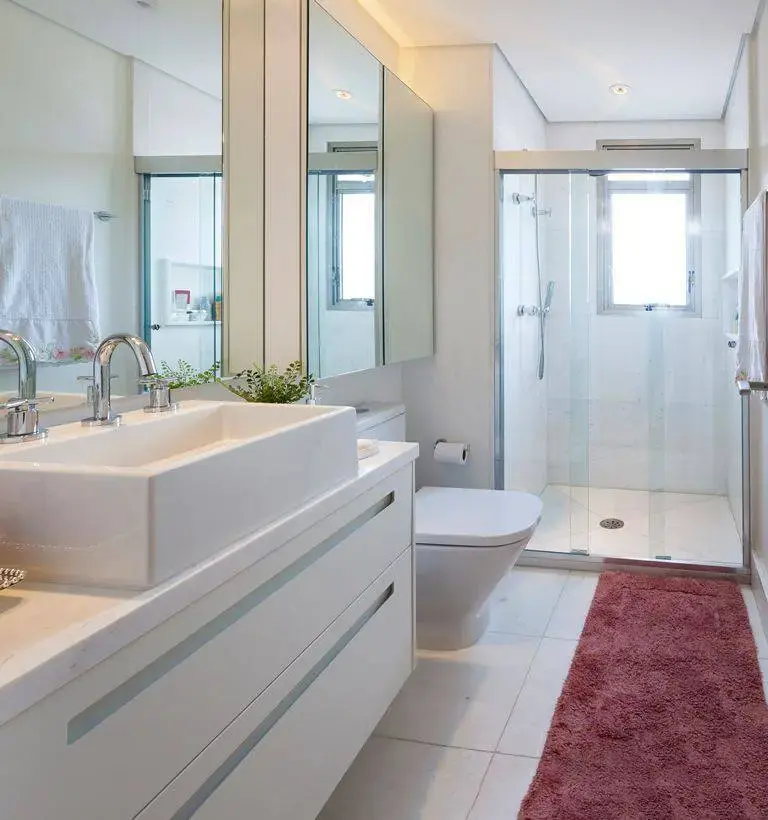 Decoração de banheiro clara com gabinete com gavetas e muitos espelhos Projeto de Luciana Tomas