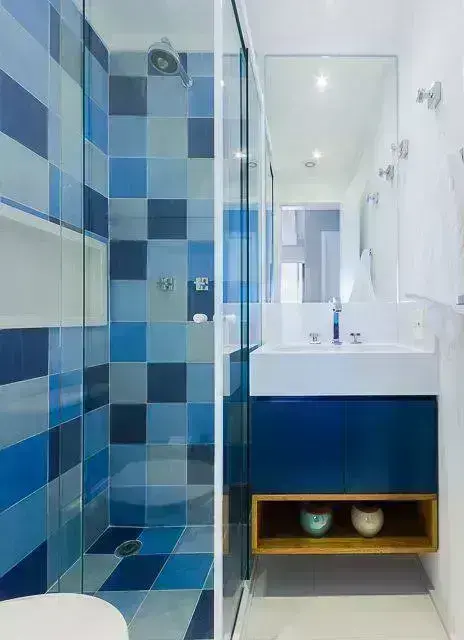 Decoração de banheiro colorida com gabinete azul e nicho branco Projeto de Duda Senna