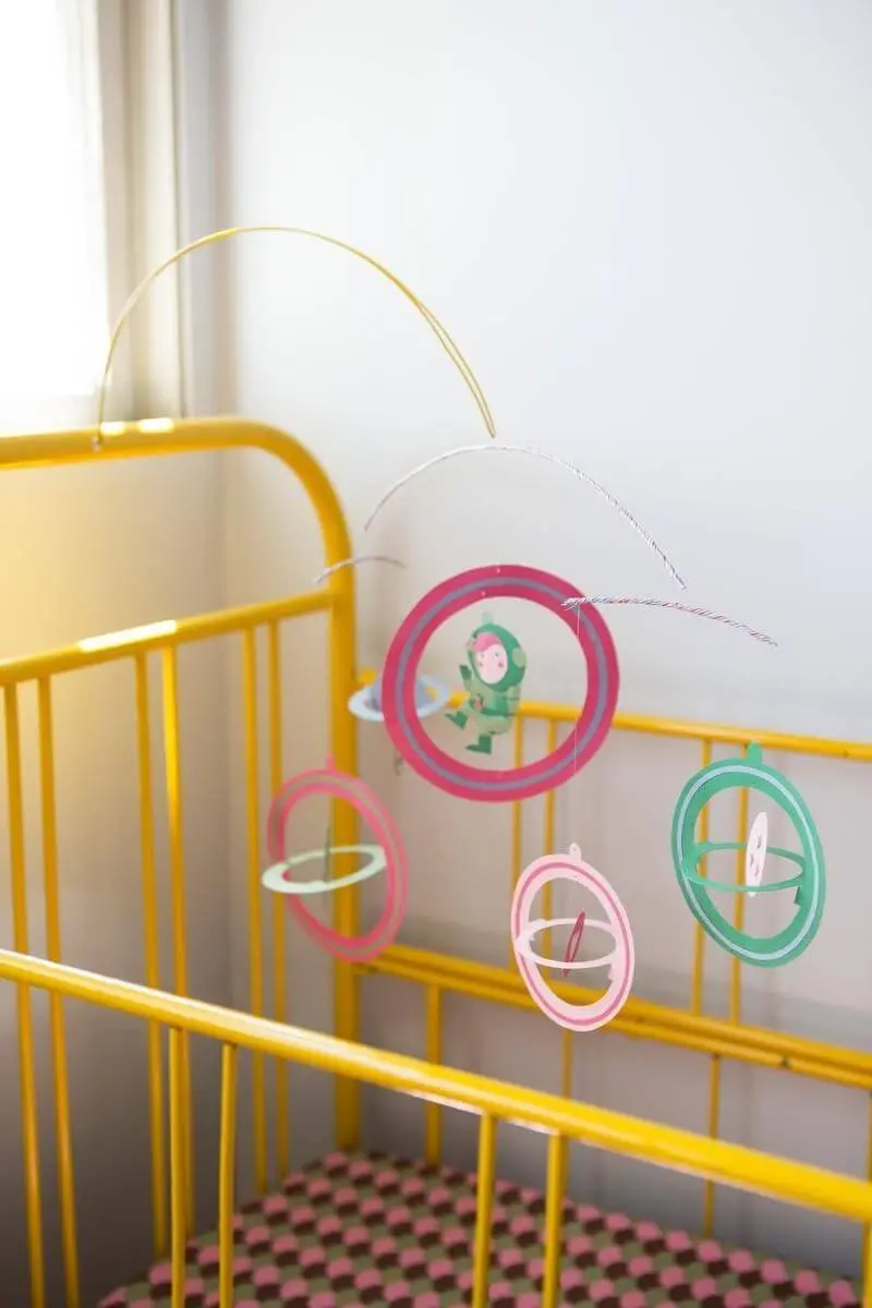 Decoração de quarto de bebê com berço amarelo e móbile colorido Projeto de Buji