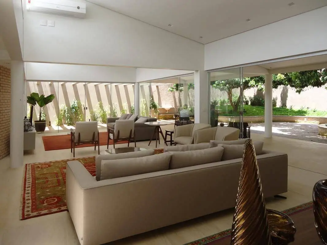 Sala de estar ampla com tapetes para sala delimitando espaços Projeto de Angela Pinho