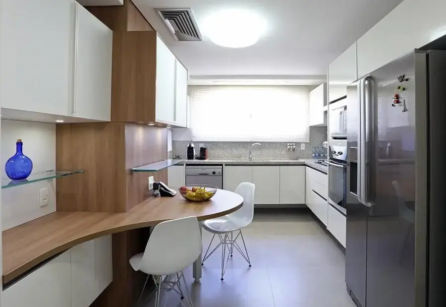 Cozinha planejada com armários brancos e bancada planejada em madeira Projeto de Fernanda Renner