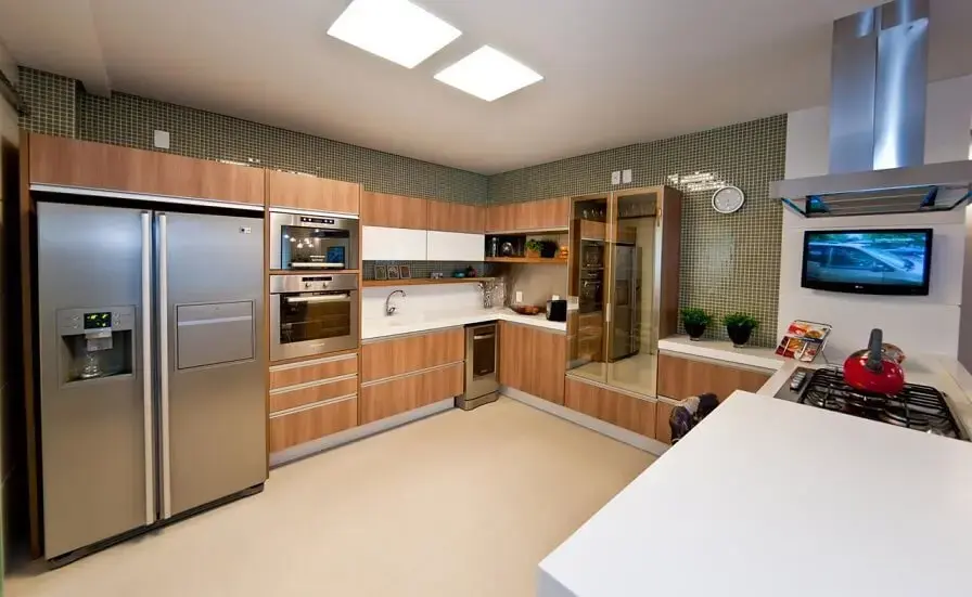 Cozinha planejada com armários em madeira e paredes revestidas em pastilhas verdes Projeto de Juliana Pippi