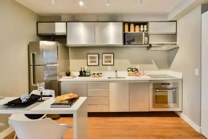 Cozinha planejada com armários metálicos e mesa pequena Projeto de Bender Arquitetura