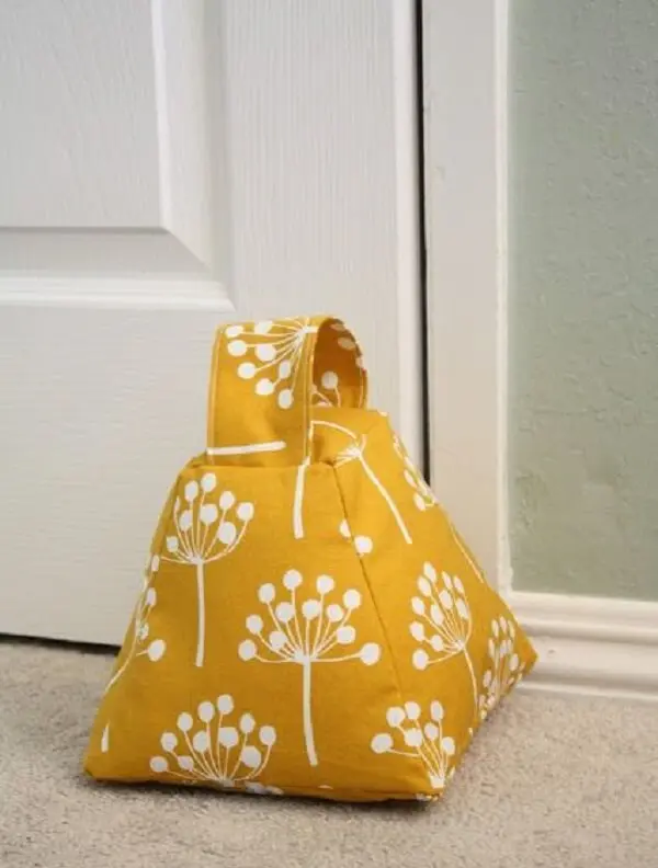 O peso de porta com tecido amarelo traz um toque de cor para a decoração. Fonte: Pinterest
