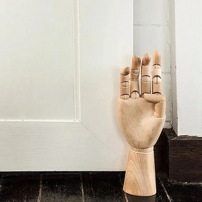 Peso de porta feito em madeira com formato de mão. Fonte: El Buen Ojo