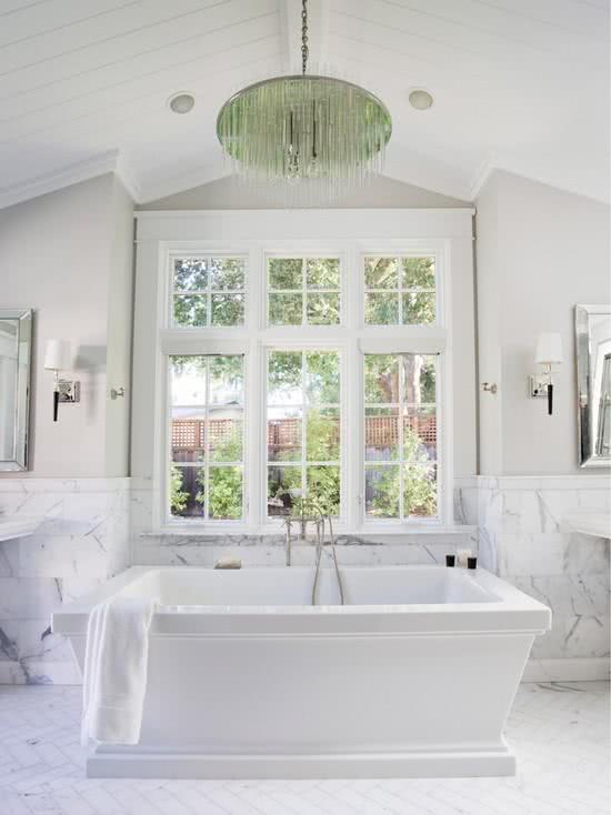 Banheiro com banheira branca e revestimento de mármore