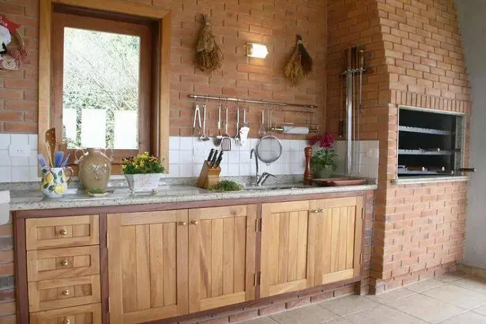 Cozinha com móveis rústicos e churrasqueira de tijolinhos