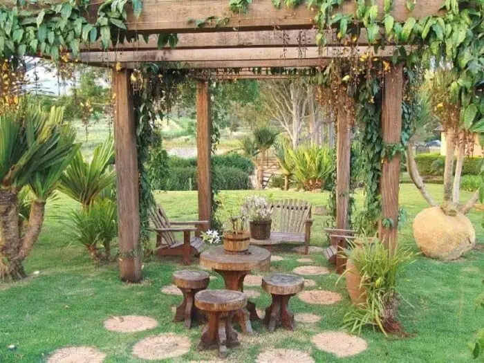 Crie um ambiente especial no jardim da casa de fazenda com pergolado de madeira e móveis de madeira