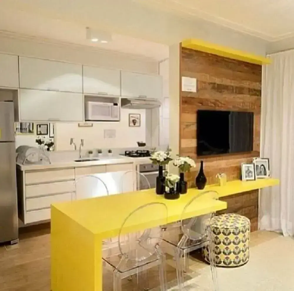 sala pequena com mesa de jantar amarela e cadeiras de acrílico