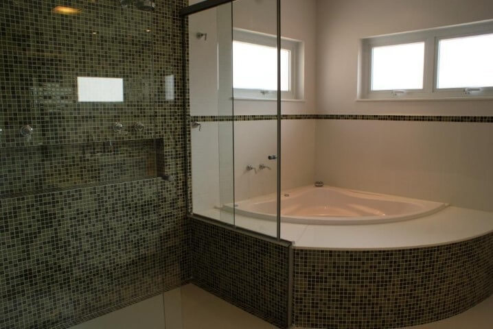 Banheiro de luxo com banheira e pastilhas escuras Projeto de Rosani Gomes