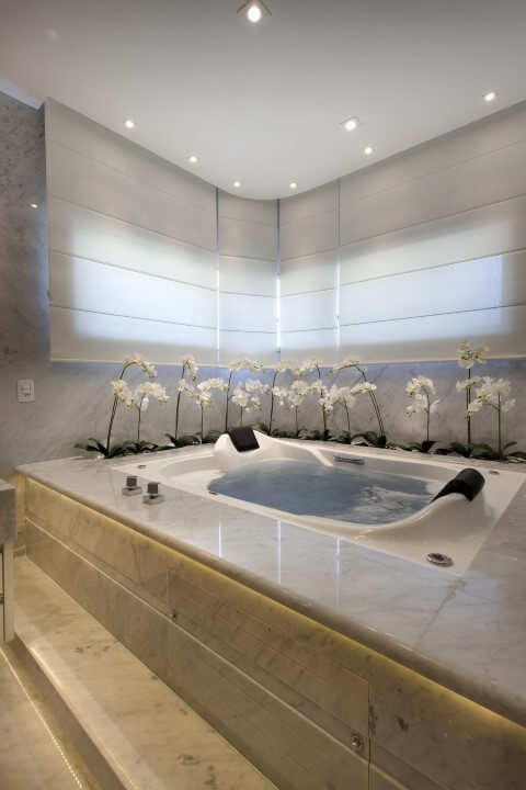 Banheiro de luxo com flores ao redor da banheira Projeto de Aquiles Nicolas Kilaris
