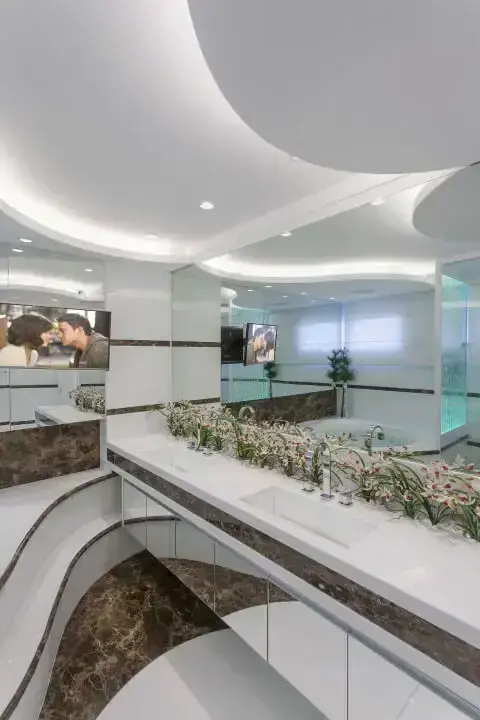 Banheiro de luxo em mármore marrom e branco e jardim Projeto de Iara Kilaris