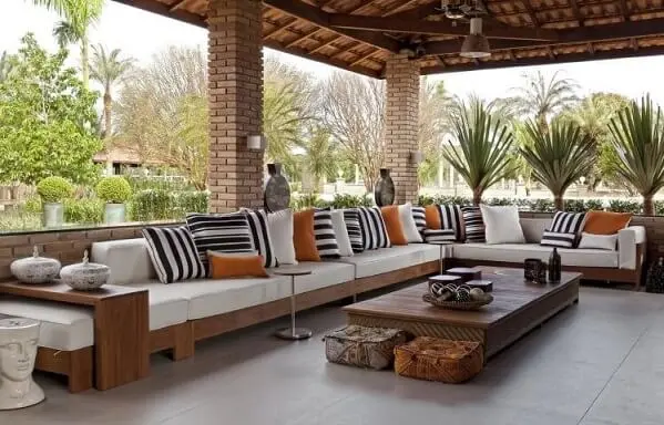 Casa com varanda com sofá em L longo Projeto de Leo Shehtman