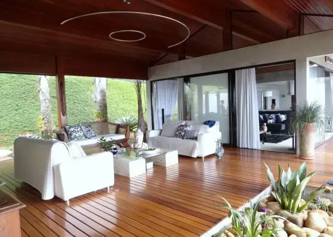 Deck de madeira na varanda com sofás brancos Projeto de DG Arquitetura