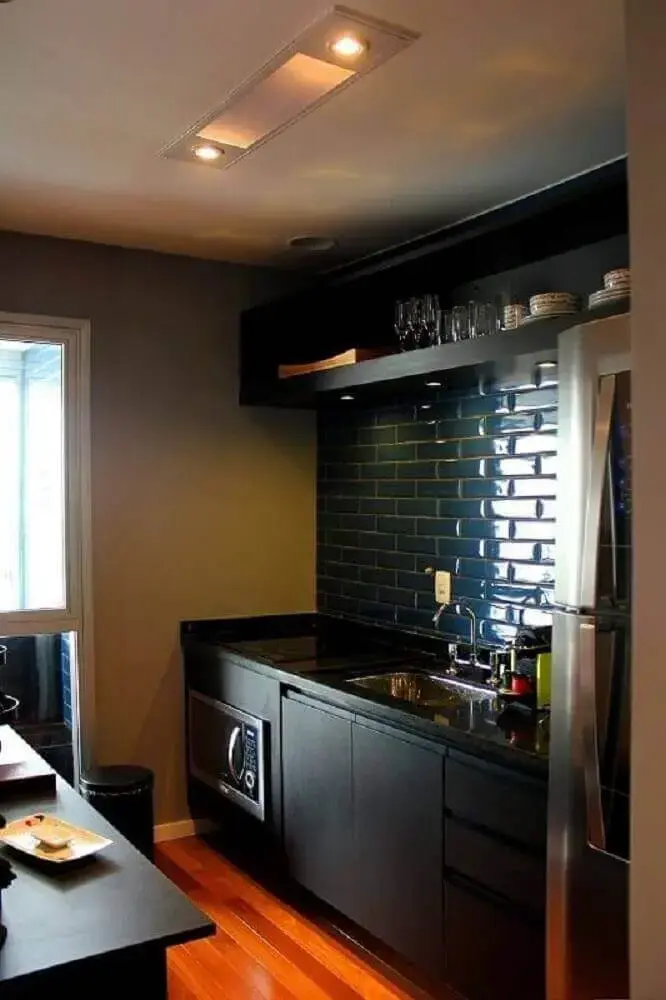 Cozinha planejada preta com ladrilho hidráulico e piso de madeira