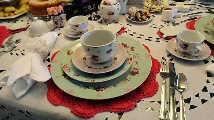 Sousplat de crochê vermelho com pratos floridos