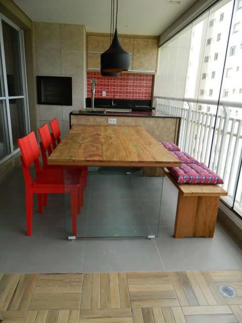 Varanda com churrasqueira com mesa com base de vidro Projeto de Adriana Victorelli