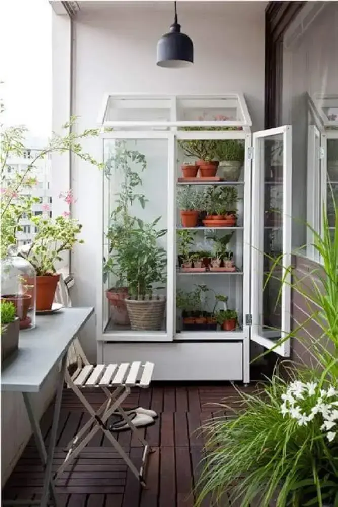varanda com armário de vidro como suporte para vasos de plantas. 