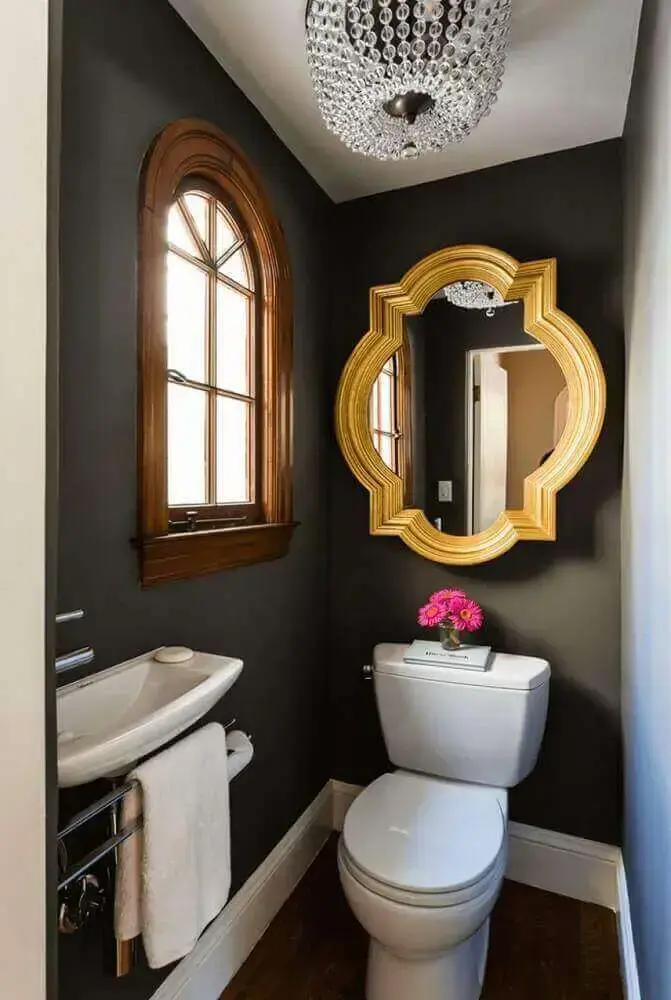 decoração de banheiro pequeno com parede preta e espelho dourado