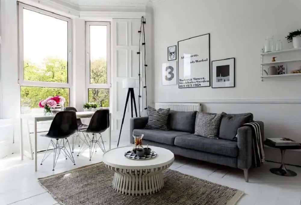 decoração de sala neutra com sofá cinza e cadeiras pretas. 