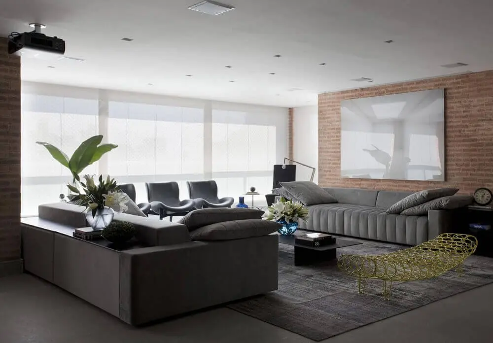 sala com sofá cinza e parede de tijolinho