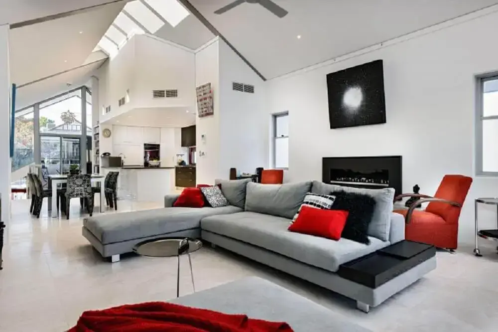 sala de estar com sofá retrátil cinza e almofadas vermelhas