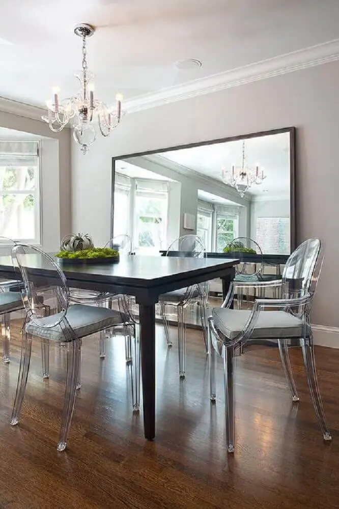 sala de jantar com espelho apoiado no piso e cadeiras de acrílico