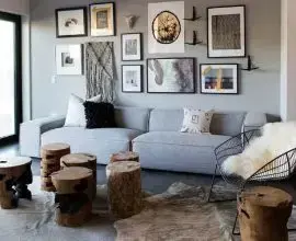 sofá cinza para sala de estar decorada com tapete de coouro e troncos de madeira